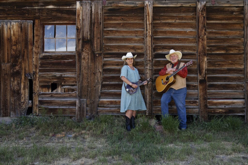 Couple with guitars in front of their barn for homestead legacy video