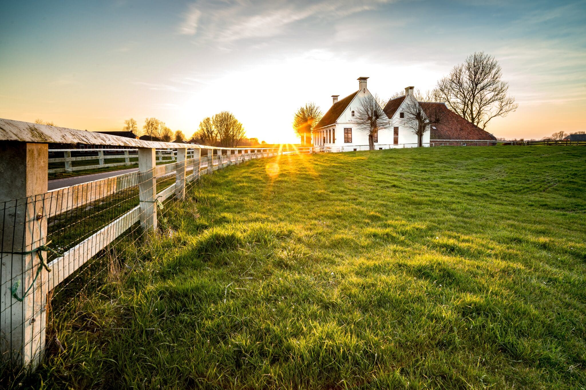 Historic farmhouse with a beautiful sunset backdrop, showcasing generations of family memories.