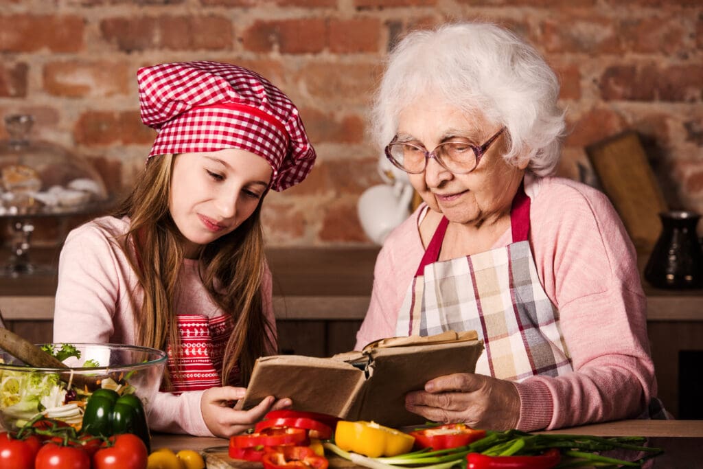 Grandmother and granddaughter reading a recipe book to preserve a family tradition.